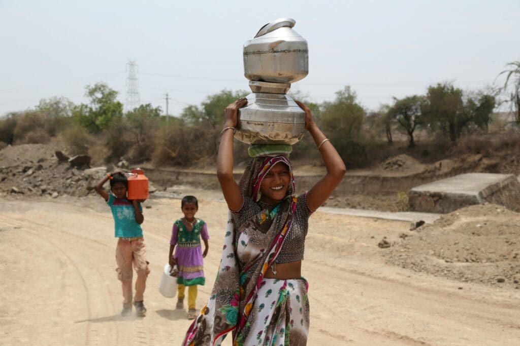 Image: woman in green and white dress holding white ceramic jar