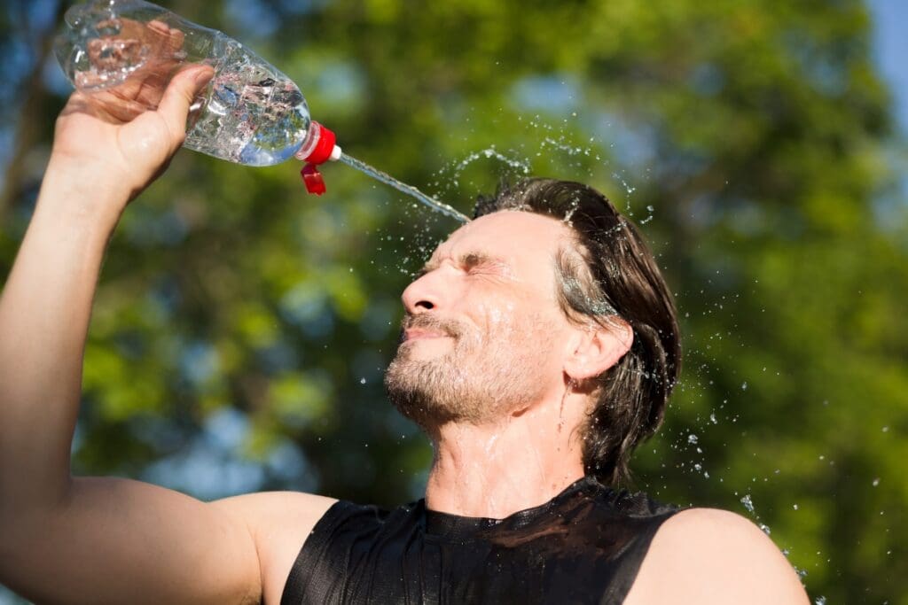 Fitness runner drinking and splashing water in his face