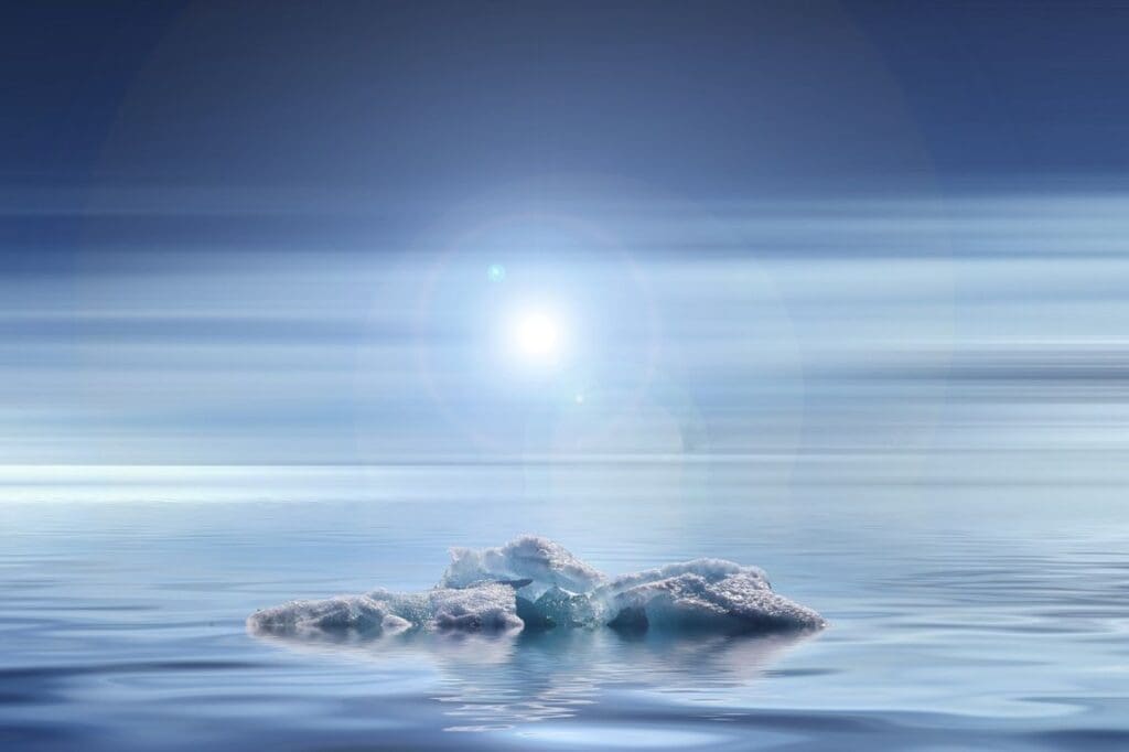 Small iceberg floating in ocean water under a bright sky with the Sun visible above - climate change effects (s. science, climate, Muser)