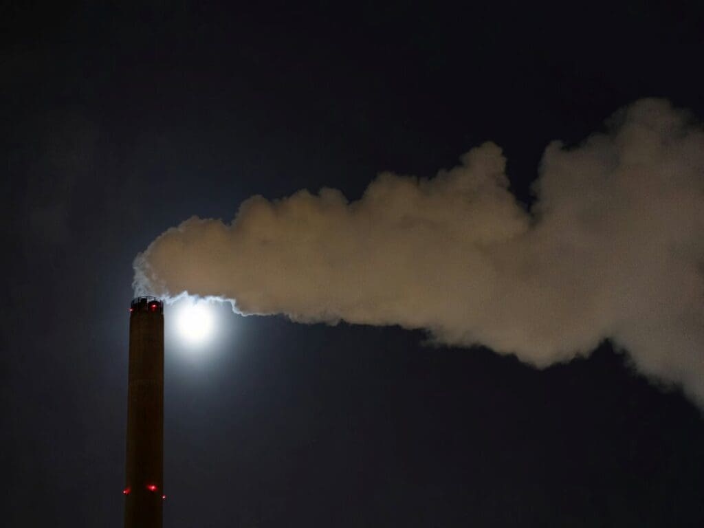 Home Image: a smokestack emits from a chimney at night