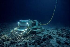Home Image: Illustration of an uncrewed deep-sea mining machine operating on the seabed, connected by a cable to a surface vessel above while disturbing sediment on the ocean floor (AI-Generated)