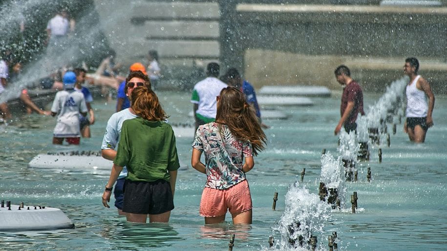 Image: People cool off beside the Trocadéro fountains in Paris during a hot summer day