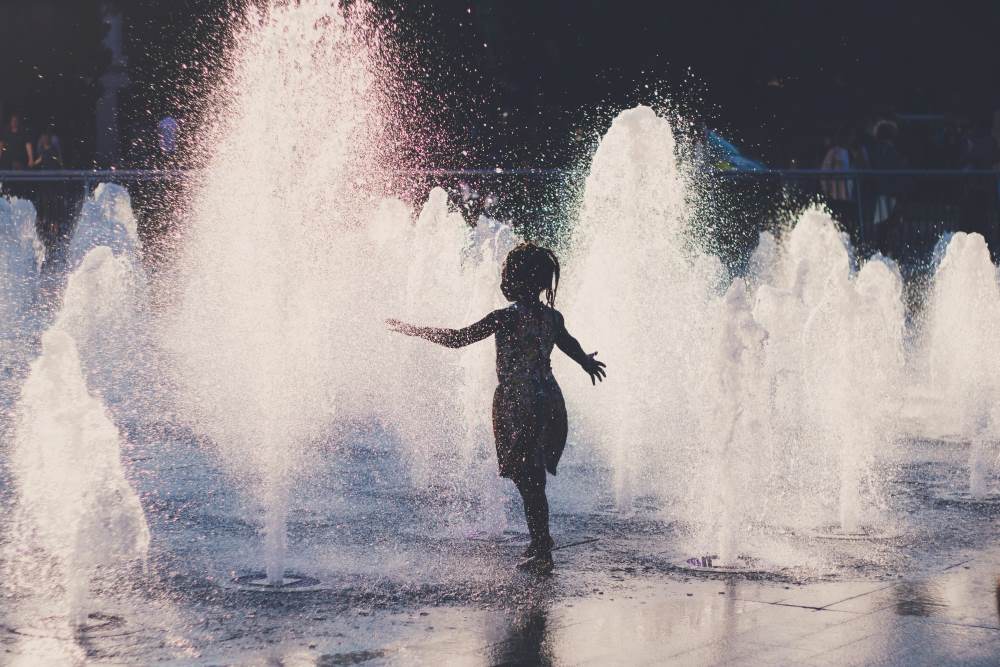 Image: girl cools off in a water fountain