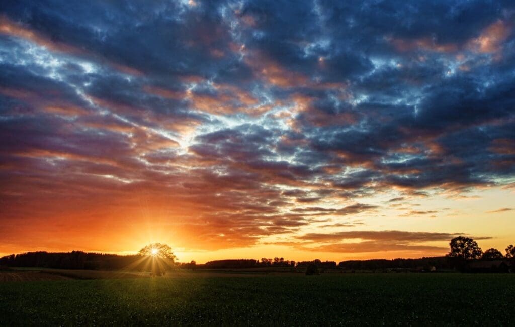 Image: A vibrant sunset over a tranquil countryside field