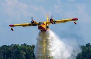 Home Image: A firefighting aircraft releasing water to combat a forest fire