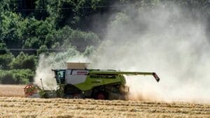 Home Image: Green-red combine harvester working in a golden, dusty field