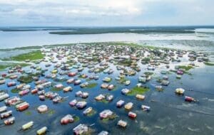 Home Image: houses on a flooded lake under a cloudy sky (s. climate change, 1.5C overshooting limit)