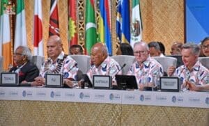 Home Image: Delegates seated at the Pre-COP31 climate meeting in Fiji, with country placards and Pacific national flags behind them